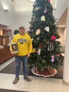 Our 2022 boarder battle winner posing by a lobby Christmas tree