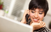 Woman Talking on the Phone While Using a Laptop