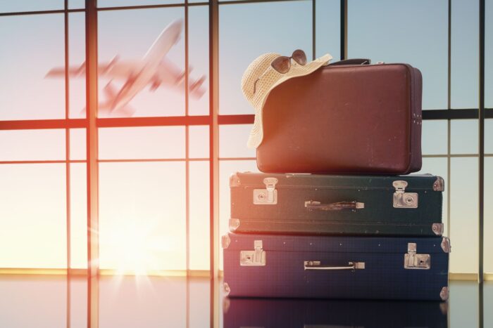 stack of suitcases in an airport with a summer hat and sun glasse resting on the cases