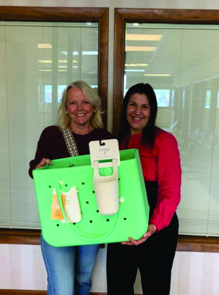 Two ladies holding a vinyl bag with some small stuff in it.